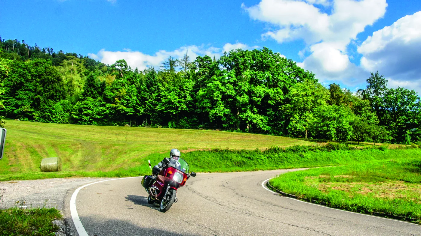 Motorrad auf einer Landstraße durch Wiesen und Wald Motorrad auf einer Landstraße durch Wiesen und Wald